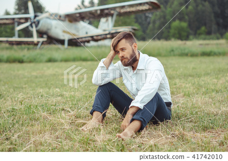 a man sitting on the grass at the old plane a man sitting on the grass at the old plane 41742010