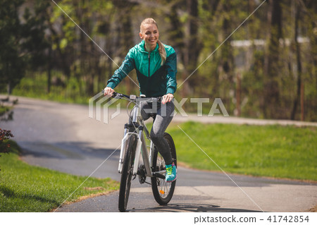 Cheerful woman with bike is relaxing outdoors Cheerful woman with bike is relaxing outdoors 41742854