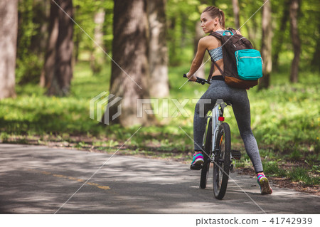 Young woman is travelling through forest on bike Young woman is travelling through forest on bike 41742939