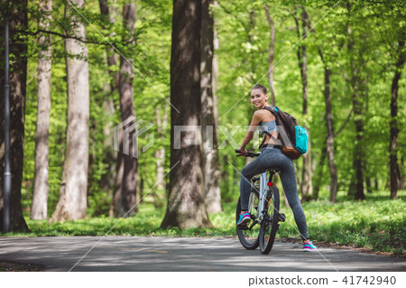 Joyful woman is riding bicycle in forest Joyful woman is riding bicycle in forest 41742940