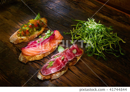 Assorted bruschetta with roast beef, vegetables and lightly salted salmon with greens leaves on 41744844