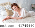 Pretty sexy young woman in a white bodoir dress laying on a bed 41745440