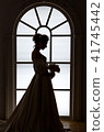 Beautiful bride stands silhouette near window 41745442