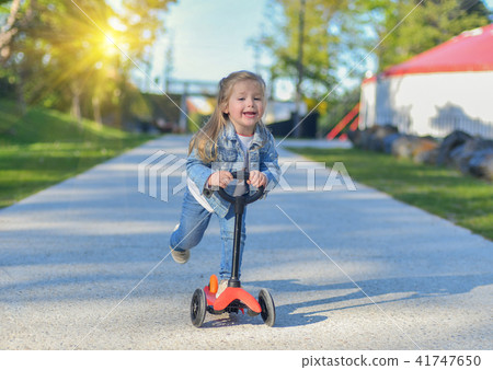 Little girl is riding a scooter Little girl is riding a scooter 41747650