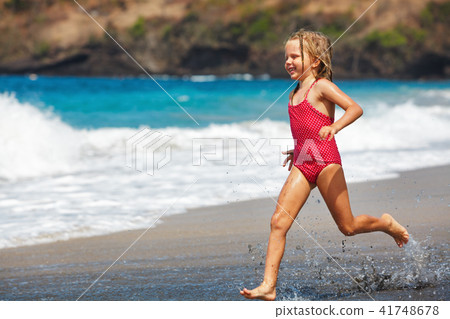 Happy girl run along sea surf by sand beach 41748678