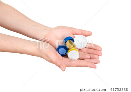 Female hand holding plastic bottle caps. Two hands Female hand holding plastic bottle caps. Two hands 41758288
