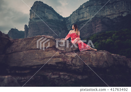 Young beautiful woman in red dress looking on mountains. Spain, Sant Roma de Sau. Young beautiful woman in red dress looking on mountains. Spain, Sant Roma de Sau. 41763492