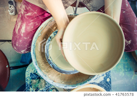 Potter holds round clay plate in his hands. Potter holds round clay plate in his hands. 41763578