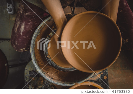 Potter holds round clay plate in his hands. Potter holds round clay plate in his hands. 41763580