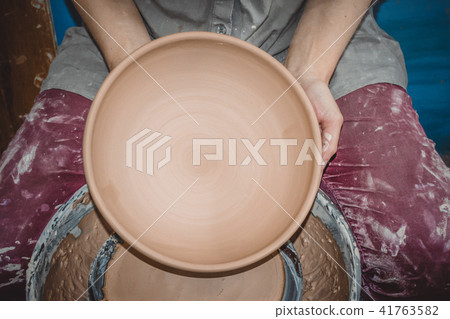 Potter holds round clay plate in his hands. Potter holds round clay plate in his hands. 41763582