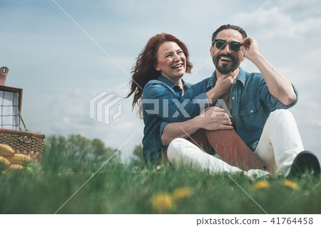 Joyful married couple having picnic on grassland  41764458