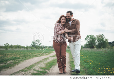 Cheerful loving couple walking on green field Cheerful loving couple walking on green field 41764530