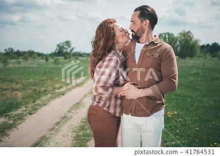 Cute mature loving couple bonding to each other on grassland Cute mature loving couple bonding to each other on grassland 41764531
