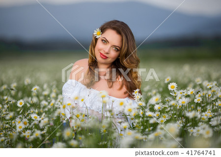 Beautiful woman on the camomile field is wearing white dress, spring time 41764741