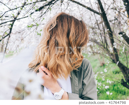 Young woman with fluttering blonde hair standing 41764798