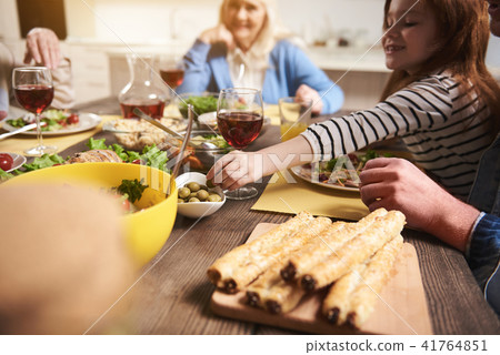 Small delighted girl eating at table with family Small delighted girl eating at table with family 41764851