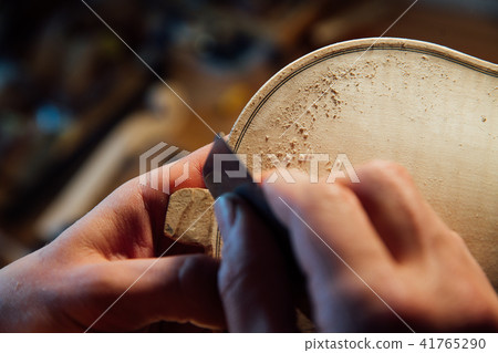 Master artisan luthier working on the creation of a violin. painstaking detailed work on wood. Master artisan luthier working on the creation of a violin. painstaking detailed work on wood. 41765290