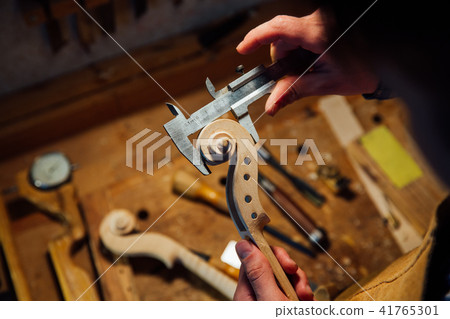 Master artisan luthier working on creation of a violin scroll. detailed work on wood with tools. Master artisan luthier working on creation of a violin scroll. detailed work on wood with tools. 41765301