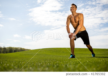 Grinning athlete is exercising on lawn 41765302