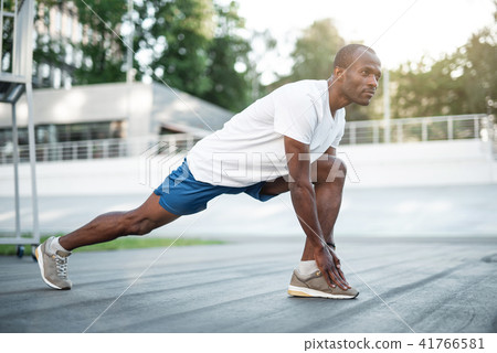 Focused male athlete workouting on stadium 41766581