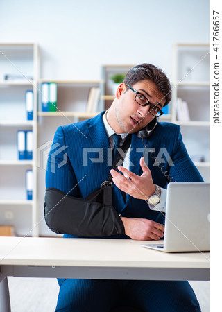 Businessman with broken arm working in office 41766657