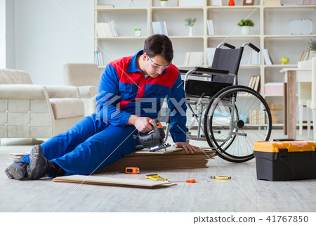 Disabled man laying floor laminate in office Disabled man laying floor laminate in office 41767850