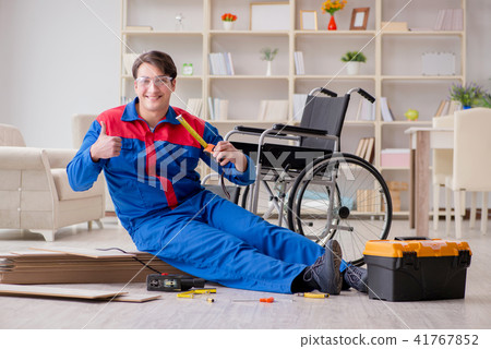Disabled man laying floor laminate in office Disabled man laying floor laminate in office 41767852