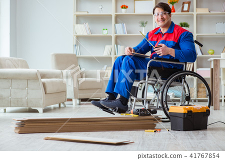 Disabled man laying floor laminate in office Disabled man laying floor laminate in office 41767854
