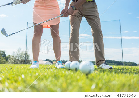 Low section of man and woman holding iron clubs while practicing Low section of man and woman holding iron clubs while practicing 41771549
