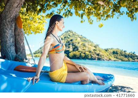 Beautiful woman sitting on boat close to the ocean beach Beautiful woman sitting on boat close to the ocean beach 41771660