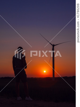 Man looking windmills at sunset. 41780208