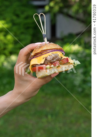 Woman's hand with a homemade burger. Woman's hand with a homemade burger. 41780319