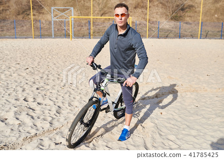 Cyclist with bike on the sand 41785425