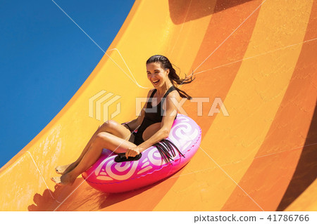 young woman having fun on the water slide in aqua park 41786766