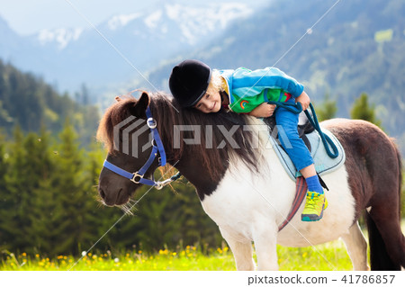 Kids riding pony. Child on horse in Alps mountains Kids riding pony. Child on horse in Alps mountains 41786857