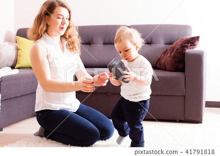 Young mother gives shoes to her small son 41791818