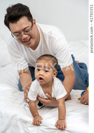 Asian father touching and playing with the boy baby on the bed in the house, Family Lifestyle Concept Asian father touching and playing with the boy baby on the bed in the house, Family Lifestyle Concept 41793351