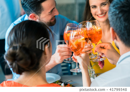 Four friends toasting together with a cold refreshing alcoholic drink Four friends toasting together with a cold refreshing alcoholic drink 41799348