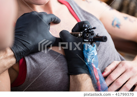 Close-up of the hands of a tattoo artist tattooing two roses 41799370