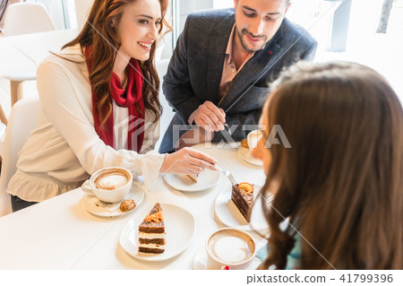 Happy couple sitting at table with their mutual friend in a trendy cafe Happy couple sitting at table with their mutual friend in a trendy cafe 41799396