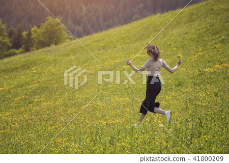 Girl with a bouquet is running on flower meadow Girl with a bouquet is running on flower meadow 41800209