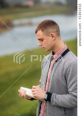 A cute student writes down his thoughts in his notebool using a pensil A cute student writes down his thoughts in his notebool using a pensil 41801918