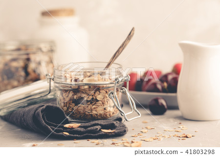 Homemade oat granola in glass jars with cherry Homemade oat granola in glass jars with cherry 41803298