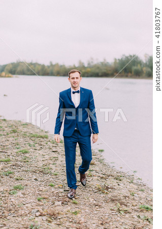 Ealking groom on the beach during the cloudy weather. Ealking groom on the beach during the cloudy weather. 41803767