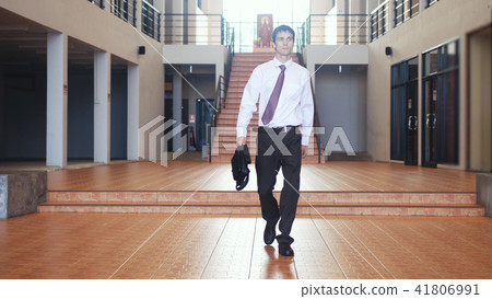 Young handsome businessman in a suit walks with a briefcase in a businesscentre . Communication 41806991