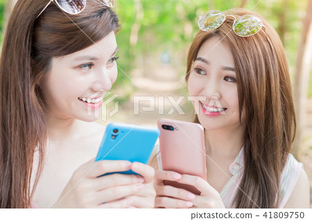 two women use phone happily 41809750