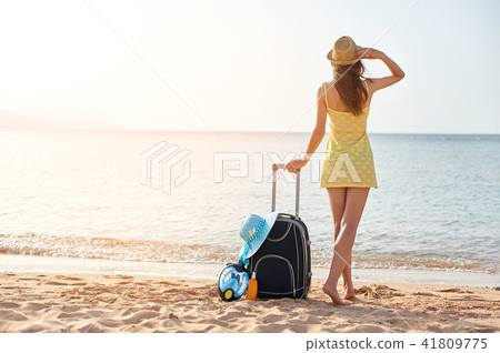 Beautiful young woman with a hat standing with suitcase on the wonderful sea background, concept of 41809775