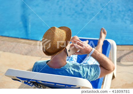 Man using mobile phone on vacation by the pool in hotel, concept of a freelancer working for himself 41809781