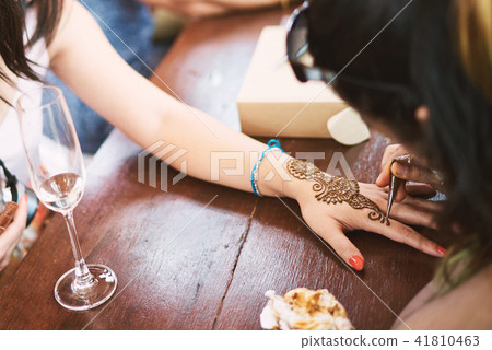 Indian henna tattoo artist drawing on women hand 41810463