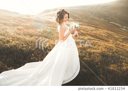 Beautiful bride with a bouquet on mountain background at sunset Beautiful bride with a bouquet on mountain background at sunset 41811234